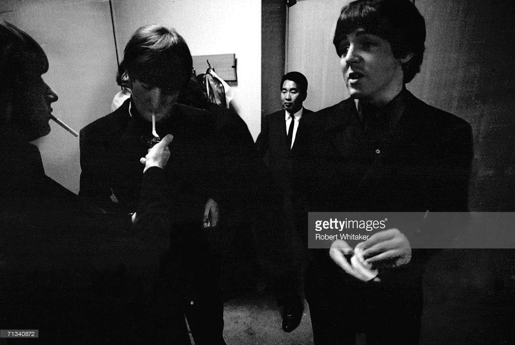 Ringo Starr lights John Lennon's cigarette backstage at the Budokan Hall, Tokyo, Japan. They are with and Paul McCartney and promoter Tatsuji Nagashima is in the background, 30th June 1966 - Credit: Robert Whitaker
