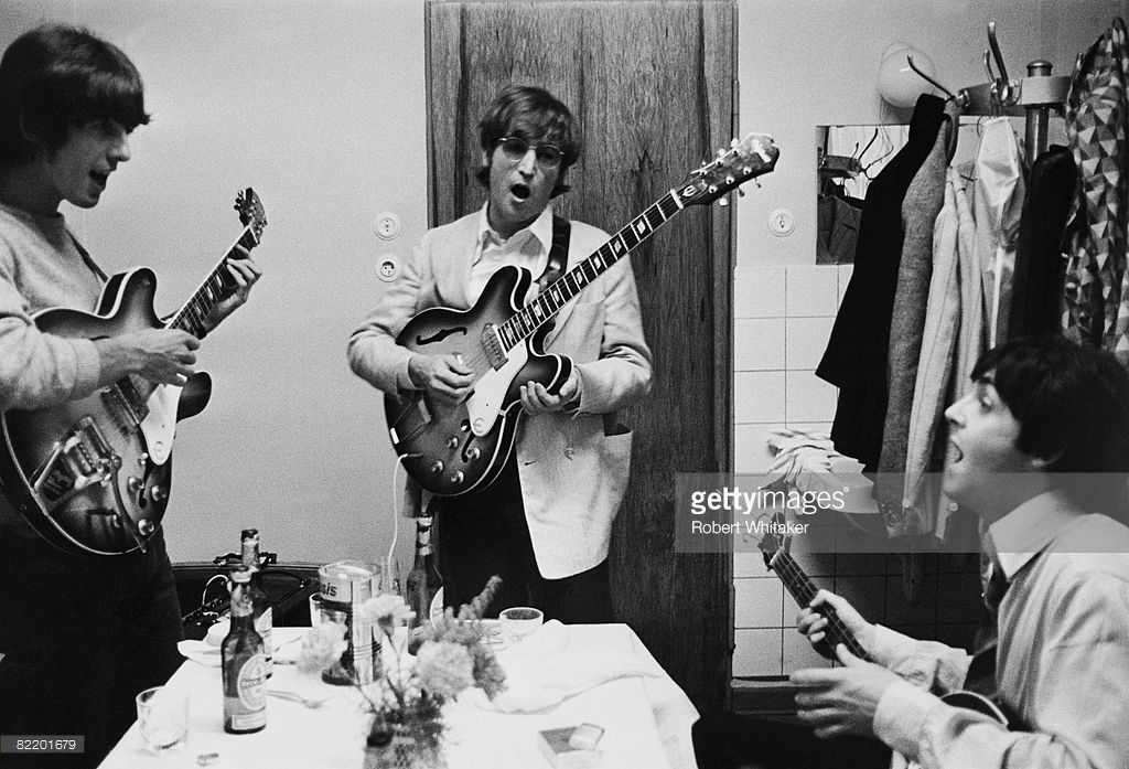 George Harrison (1943 - 2001), John Lennon (1940 - 1980) and Paul McCartney of the Beatles tuning up backstage before a concert at the Ernst Merck Halle, Hamburg, during their last world tour, 26th June 1966.
