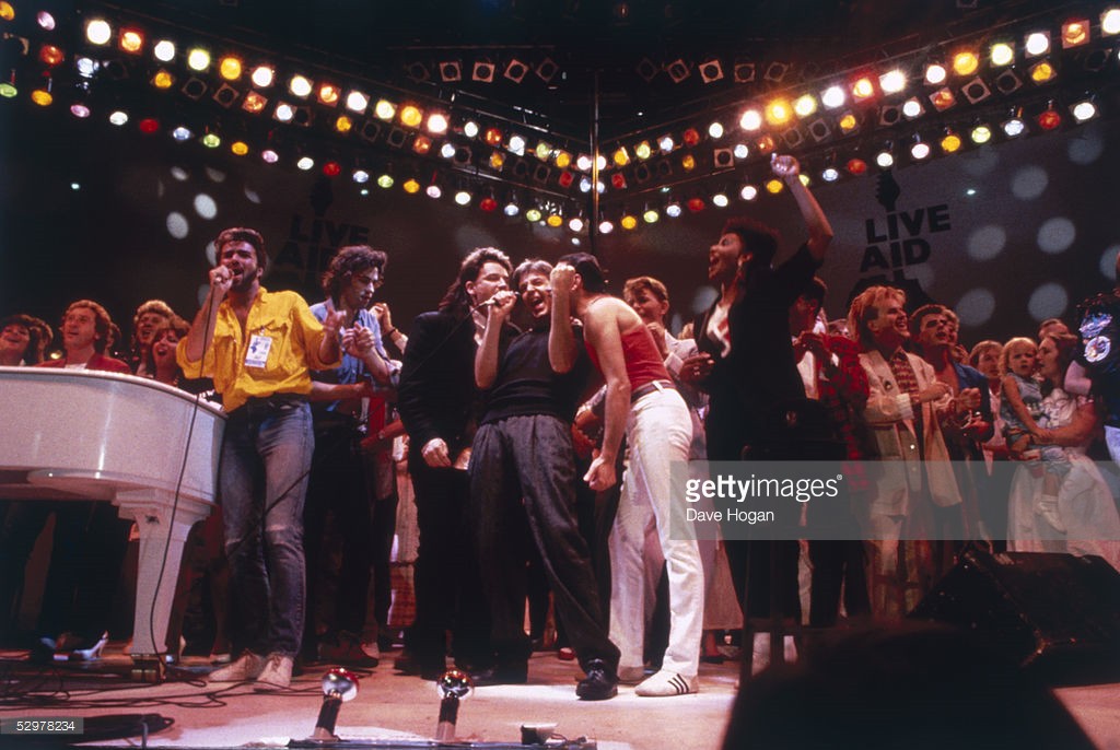 British pop acts gathered on stage for the finale of the Live Aid concert at Wembley Stadium in London, 13th July 1985. The group includes George Michael, left in yellow shirt, centre stage Bono, Paul McCartney and Freddie Mercury share a microphone, David Bowie is behind them and Howard Jones is on the right. Event organiser Bob Geldof stands next to George Michael. @Dave Hogan, Getty Images