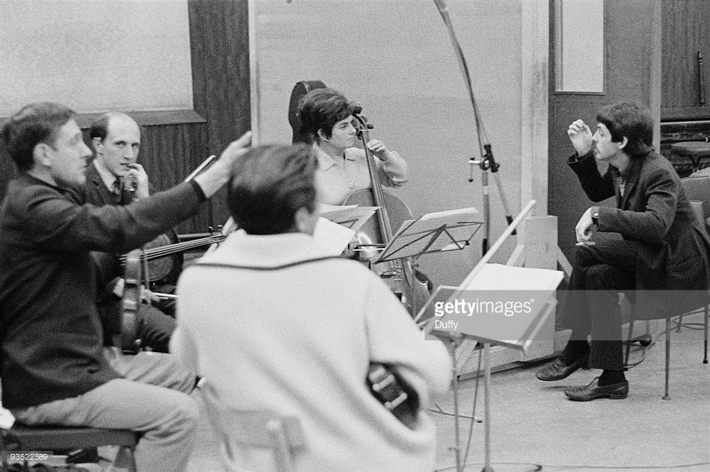 English singer, songwriter and musician Paul McCartney in a studio to record 'The Family Way', November 1966. At the back is cellist Therese Motard. Composed for the film of the same name, 'The Family Way' is considered by many to be the first Beatles solo album. A photoshoot for The Sunday Times.